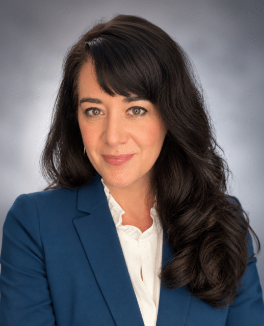 Woman with dark hair posing for a headshot. She's wearing a dark shirt.