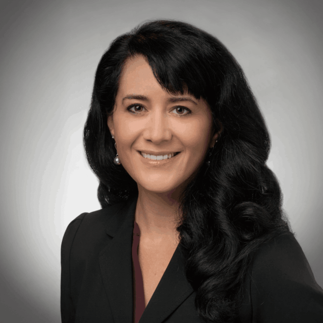 Woman with dark hair posing for a headshot. She's wearing a dark shirt.